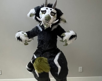 May include: A full-body furry costume in black, white, and green, with the text "Floor dragger tail belt!". The costume features a horned mask, large paws, and a tail. The costume is designed to be worn.