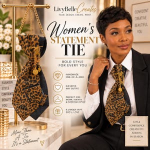 May include: A leopard print necktie with a denim backing, featuring a gold chain, a small pocket, and decorative pins. The tie is displayed on a gold stand and worn by a person in a white shirt and black blazer. Text includes Women's Statement Tie.