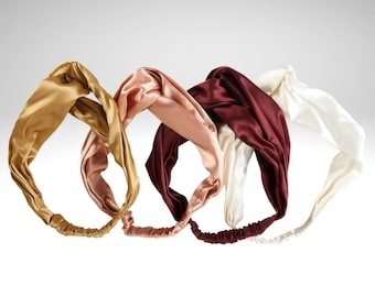 Könnte beinhalten: Vier Seiden-Haarbänder in Gold, Rosé, Burgunderrot und Elfenbein. Jedes Haarband hat ein gedrehtes Design und ein elastisches Band. Die Haarbänder sind aus einem glatten, glänzenden Stoff gefertigt. Ein stilvolles Haaraccessoire.