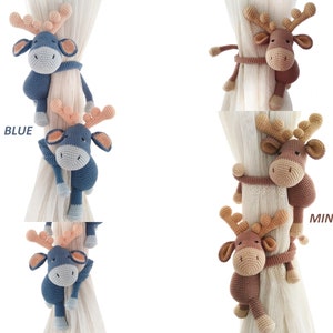May include: Two crocheted reindeer curtain tiebacks in blue and brown. The blue reindeer is labelled "BLUE" and the brown reindeer is labelled "MINK".