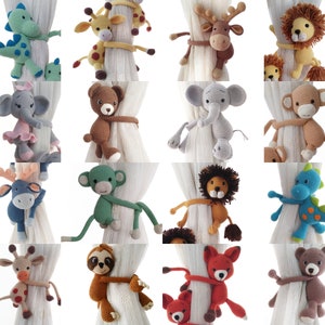 May include: A collection of 16 crocheted animal curtain tiebacks in various colours and designs, including a lion, elephant, monkey, dinosaur, reindeer, sloth, fox, and bear.