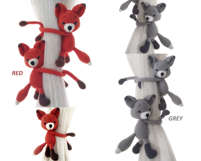 May include: Two crocheted fox curtain tiebacks, one red and one grey, are shown wrapped around a white curtain rod. The tiebacks are made of yarn and have a cute, cartoonish appearance.