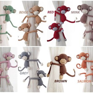 May include: Set of 10 crocheted monkey curtain tiebacks in various colours, including mint, beige, red, mink, pink, grey, brown, and salmon. Each tieback features two monkeys holding onto a curtain.