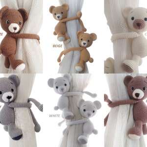 May include: Set of six crocheted teddy bear curtain tie backs in various colours: bronze, beige, cream, grey, white, and brown. Each bear is holding onto a curtain with its paws.