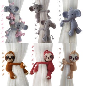 May include: Set of six crocheted animal curtain tiebacks. The tiebacks are in the shapes of elephants and sloths. The elephants are in ballerina, grey, and lilac colours. The sloths are in copper, brick, and beige colours.