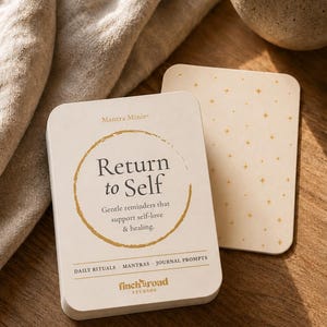 May include: A deck of cream-colored cards titled Mantra Minis Return to Self with a gold circular border and text reading Gentle reminders that support self-love & healing. The bottom includes Daily Rituals, Mantras, Journal Prompts and finch road STUDIOS.