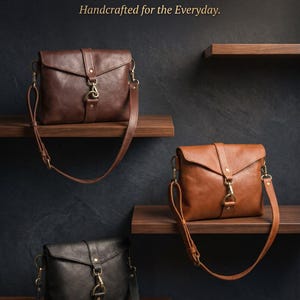 May include: Three leather crossbody bags in dark brown, tan, and black, each featuring a fold-over flap, a central metal clasp, and an adjustable shoulder strap. The text DARNIK LEATHER THE BISON COLLECTION Handcrafted for the Everyday is visible.
