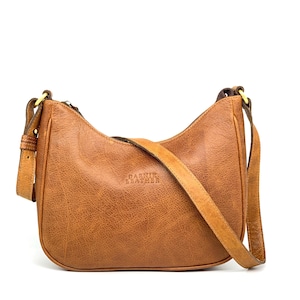 May include: A tan leather shoulder bag with a curved design and an adjustable strap. The bag features a zip closure and the brand name "BARNIV LEATHER" is embossed on the front. The bag is made of textured leather.
