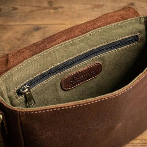 Brown bison leather crossbody sling bag with olive-green lining, zip pocket, and leather tag.