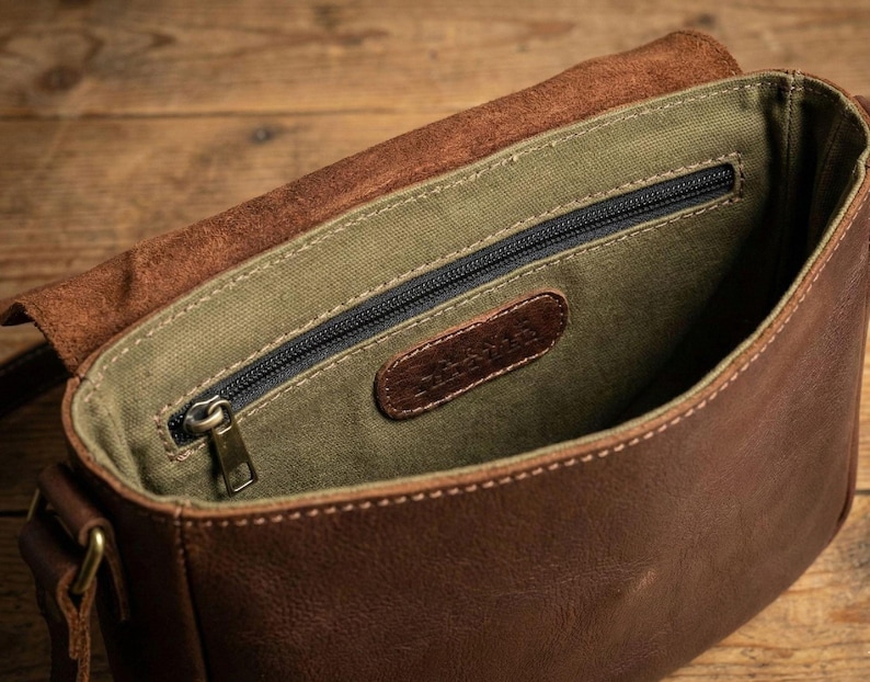 Brown bison leather crossbody sling bag with olive-green lining, zip pocket, and leather tag.