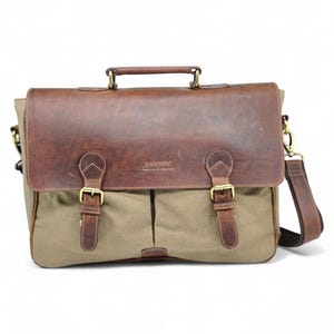 May include: A brown leather and canvas messenger bag with a top handle and adjustable shoulder strap. The bag features a leather flap with two buckle closures and a canvas body. The bag has a rectangular shape.