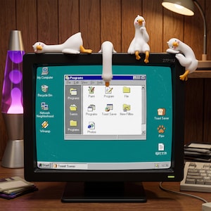Könnte beinhalten: Ein schwarzer Computermonitor mit einer Retro-Betriebssystemoberfläche und Symbolen wie My Computer, Recycle Bin und Toast Saver. Vier weiße Gänsefiguren mit orangefarbenen Schnäbeln und Füßen sitzen auf dem oberen Rand des Monitorrahmens.