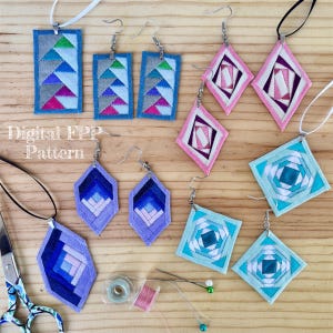 May include: A collection of fabric pendants and earrings featuring geometric patchwork designs in blue, pink, purple, and teal. The set includes rectangular, diamond, and square shapes with stitched details. Text reads Digital FPP Pattern.