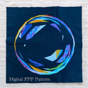 Op de afbeelding: Een donkerblauwe quilt met een cirkelvormig ontwerp bestaande uit kleurrijke geometrische vormen. Het ontwerp bevat een regenboog aan kleuren, waaronder blauw, paars, geel en groen. De tekst "Digital FPP Pattern" staat onderaan de quilt.