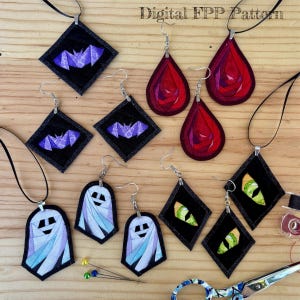 May include: A collection of fabric-based jewellery pieces featuring bat, rose, mummy, and cat eye designs. The items include pendants on black cords and dangling earrings with metal hooks. The text Digital FPP Pattern is visible.
