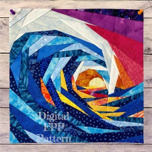May include: A square fabric art piece with a spiral design in shades of blue, white, orange, and purple. The center features a sun-like shape. The text "Digital EPP Pattern" is visible on the lower left. The piece is pinned to a wooden surface.