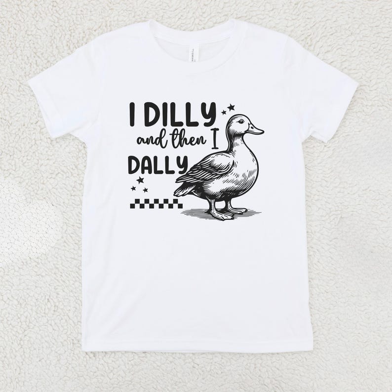Pu&ograve; includere: T-shirt bianca con la frase "I DILLY and then I DALLY" in testo nero, accompagnata da un'illustrazione dettagliata in bianco e nero di un'anatra. Il design include stelle e un motivo a scacchiera.