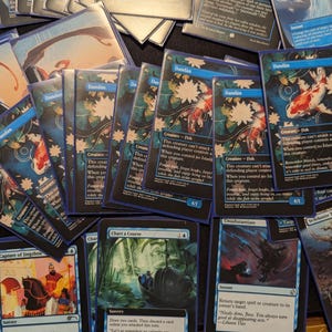 Może przedstawiać: Kolekcja kart kolekcjonerskich Magic: The Gathering. Karty przedstawiają różne ilustracje, w tym rybę koi, wzory kwiatowe i tekst. Dominujące kolory to niebieski, biały, czerwony i czarny. Niektóre karty są oznaczone jako "Dandan".