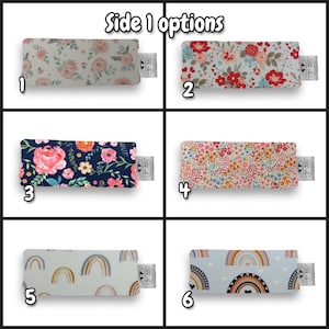 May include: A grid of six rectangular fabric swatches labeled Side 1 options. Each swatch features a unique pattern: pink floral on white, red and blue floral, pink floral on navy, small multi-colored floral, beige rainbows, and blue rainbows.
