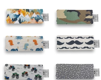 May include: Six rectangular fabric clubfoot bar covers with various patterns including a mountain landscape, camouflage, dinosaurs, mustaches, monster trucks, and arrows. Each cover features a small white brand tag on the right side.