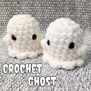 May include: Two handmade crochet ghosts in a soft, textured white yarn. Each ghost has black button eyes and a small pink blush. The image includes the text "CROCHET GHOST" in a bold, outlined font. The ghosts are on a grey, textured background.