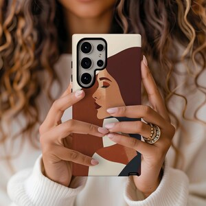 May include: A phone case with a beige background and a colorful abstract design featuring a woman's face. The case has a black camera cutout and a black border.