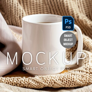 May include: White ceramic mug with a brown liquid inside, sitting on a beige knitted blanket. The mug has the text "MOCKUP SMART OBJECT PSD" printed on the side.