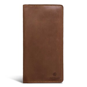 May include: A brown leather wallet with a rectangular shape. The wallet has a stitched border and a logo of a horse. The wallet is approximately 7 inches long and 3.5 inches wide.