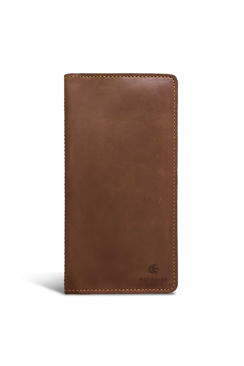 May include: A brown leather wallet with a rectangular shape. The wallet has a stitched border and a logo of a horse. The wallet is approximately 7 inches long and 3.5 inches wide.