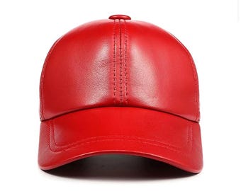 May include: A bright red baseball cap made of leather. The cap has a curved brim and a button on top. The stitching detail runs down the center of the cap.