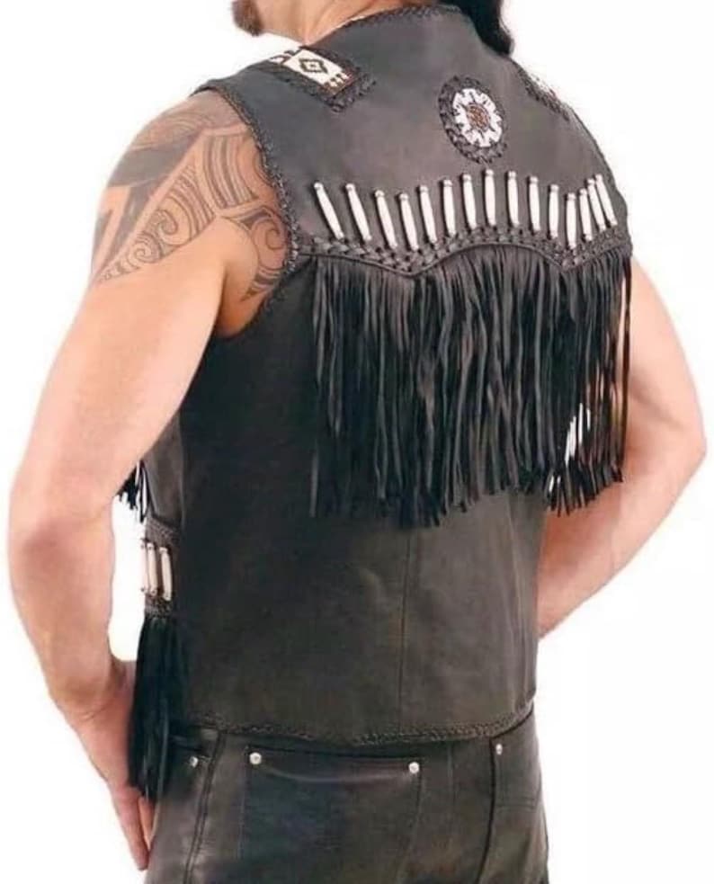 May include: Black leather vest with fringe and decorative beading. The vest features white and tan beads along the shoulders and back, with long black fringe along the bottom. The vest is sleeveless and has a classic biker style.