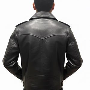 May include: Black leather jacket with a classic design, featuring a notched collar, shoulder epaulets, and a tailored fit. The jacket has a zipper closure and a decorative back panel. A timeless piece of outerwear.