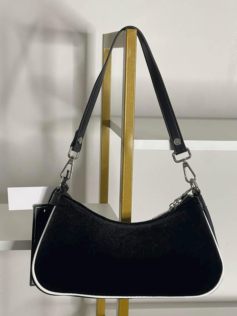 以下が含まれることがあります： 黒い持ち手と「But First, Coffee」のテキストが黒い太字で書かれた白いセラミックマグ。マグは白い表面に置かれています。マグの高さは約10cmです。