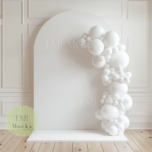 Peut inclure: Arche de ballons blancs sur fond blanc avec une plateforme blanche devant un mur blanc. L'arche est composée de ballons blancs de différentes tailles. Le texte "EMI Mocks" est visible sur le mur.
