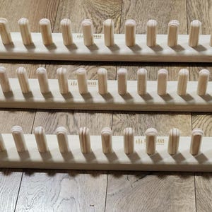 May include: Three wooden knitting looms with pegs for holding yarn. The looms are made of natural wood and have a smooth finish.