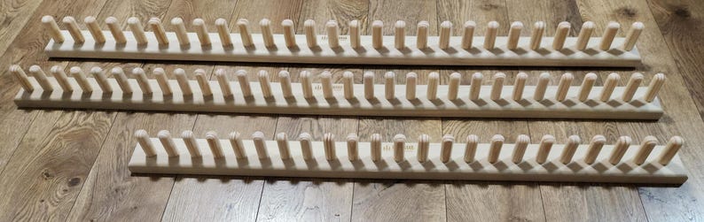 May include: Three wooden knitting looms with pegs for holding yarn. The looms are made of natural wood and have a smooth finish.