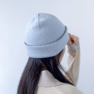 May include: A light blue beanie with a dark grey trim. The beanie is made of a soft, knitted fabric.