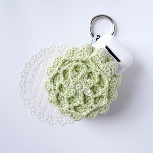 Pu&ograve; includere: Una custodia in crochet verde chiaro per un paio di auricolari wireless con un portachiavi argentato.