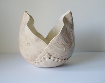 May include: A ceramic bowl with a unique, abstract design. The bowl is white with brown and gray accents and has a textured surface.