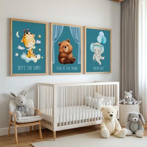 Può includere: Tre stampe artistiche incorniciate per la cameretta con animali dei cartoni animati: una giraffa, un orso e un elefante. La giraffa è su una nuvola, l'orso è seduto e l'elefante tiene in mano dei palloncini. Ogni stampa ha uno sfondo verde acqua e una cornice in legno. Il testo sulle stampe recita "SKY'S THE LIMIT!", "STAR OF THE SHOW!" e "DREAM BIG!"