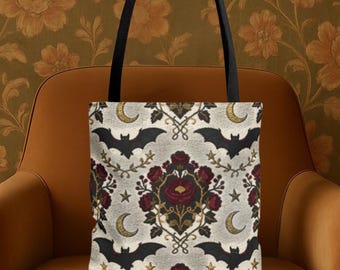 May include: Tote bag with a gothic pattern featuring black bats, crescent moons, and burgundy roses on a light gray background. The bag has black handles and is displayed on an orange chair.