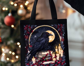 Puede incluir: Bolso tote negro con un diseño de cuervo posado sobre libros, con una luna llena y velas en el fondo. El diseño incluye un marco dorado, estrellas y detalles en rojo. El bolso tiene asas negras.