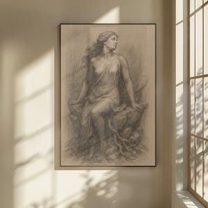 May include: A framed charcoal drawing of a seated woman in a flowing gown. The artwork, rendered in shades of gray, depicts the woman with long, flowing hair, seated on a rocky surface. The drawing is displayed in a black frame.