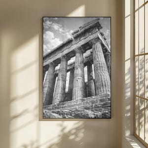 Könnte beinhalten: Schwarz-Weiß-Fotografie eines klassischen griechischen Tempels mit großen Säulen und detailliertem architektonischem Design. Das gerahmte Bild hängt an einer Wand und zeigt das historische Bauwerk vor einem bewölkten Himmel.