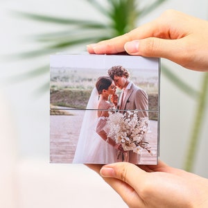 May include: A wedding photo cube with a picture of a bride and groom kissing. The cube is made of wood and has a white background.
