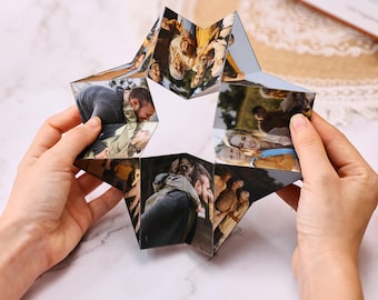May include: A star-shaped photo display featuring multiple images of people. The display is held open, showcasing various photographs. The images appear to be of people in outdoor settings. The display is held by two hands.
