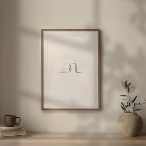 May include: A framed black and white line drawing of two abstract shapes. The drawing is in a light wood frame and is hanging on a white wall. A small potted plant is on a wooden table in front of the frame.