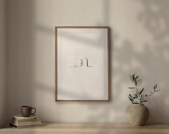May include: A framed black and white line drawing of two abstract shapes. The drawing is in a light wood frame and is hanging on a white wall. A small potted plant is on a wooden table in front of the frame.