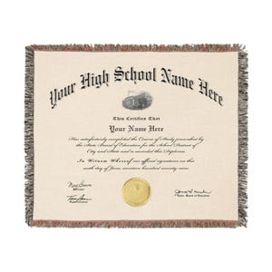 May include: A woven throw blanket featuring a high school diploma design. The diploma text includes "Your High School Name Here" and "Your Name Here". The blanket has a cream background with black text and a decorative border.