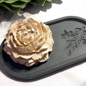 A latte colored aromatherapy home fragrance aroma Stone that is sitting on a charcoal gray tray in a cottage core decorated entryway